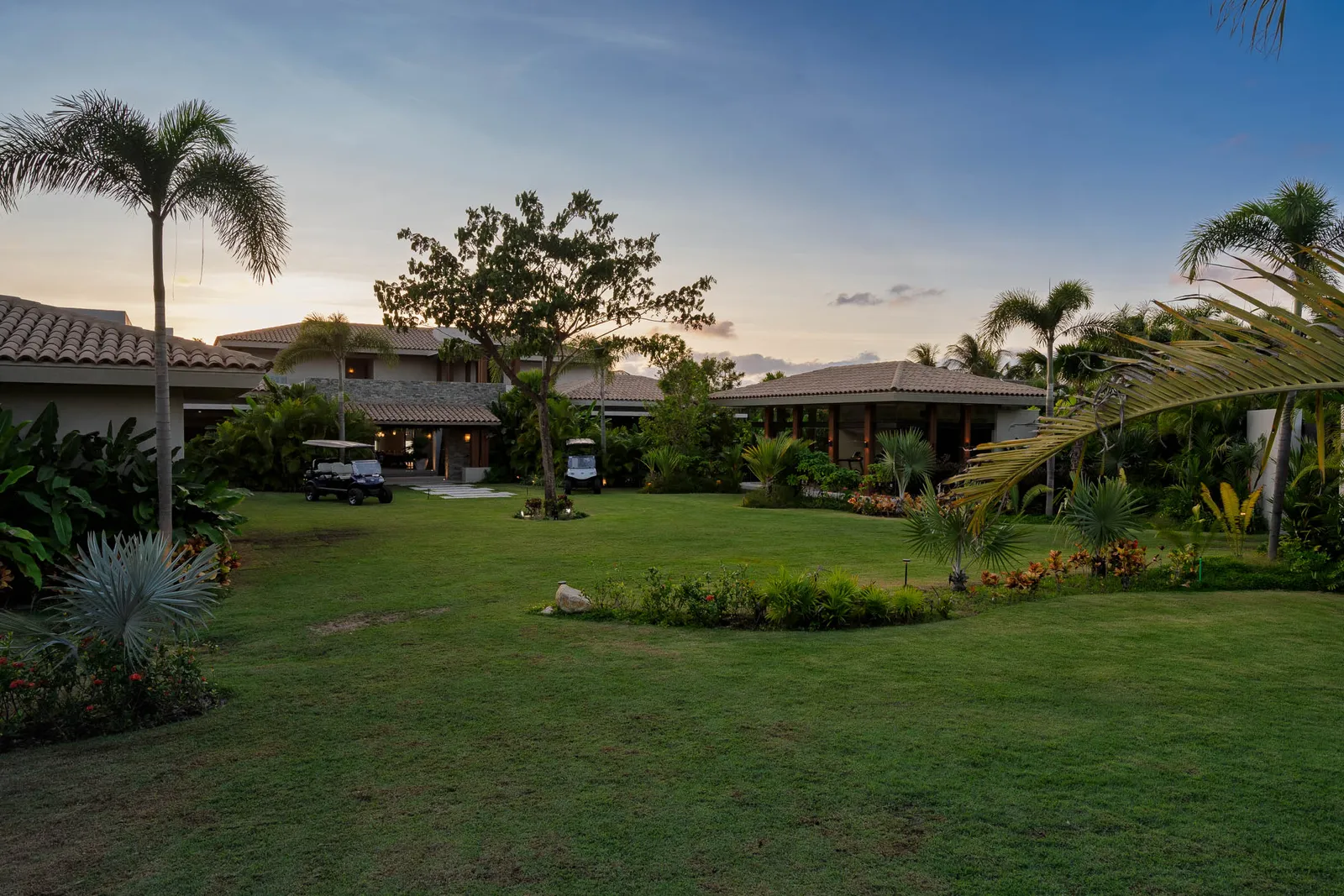 The entry lawn and gardens at dusk, palms against the last light