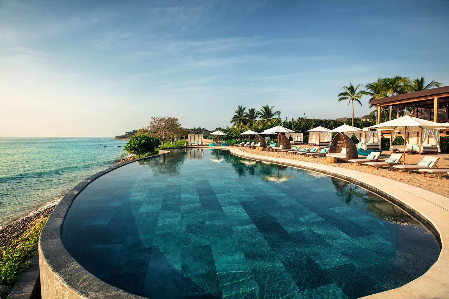 Sufi Ocean Club — the dark-tiled infinity pool reaching toward Banderas Bay, loungers and palms along its edge