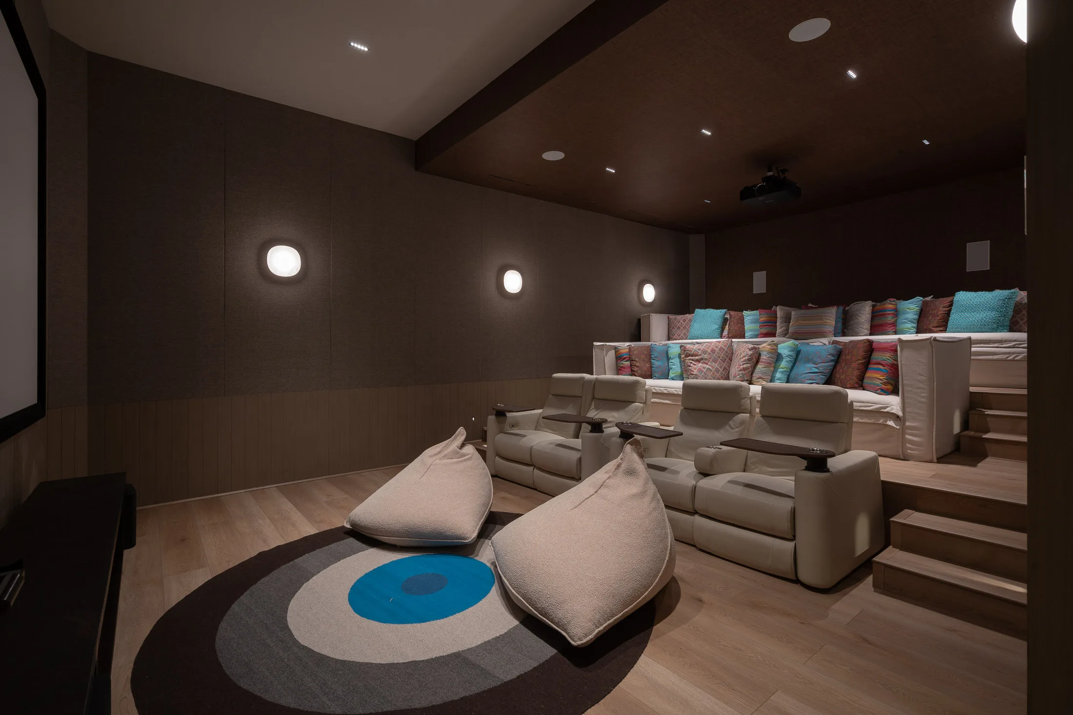 The cinema — tiered plush seats stepping up toward the back, beanbags on the rug up front