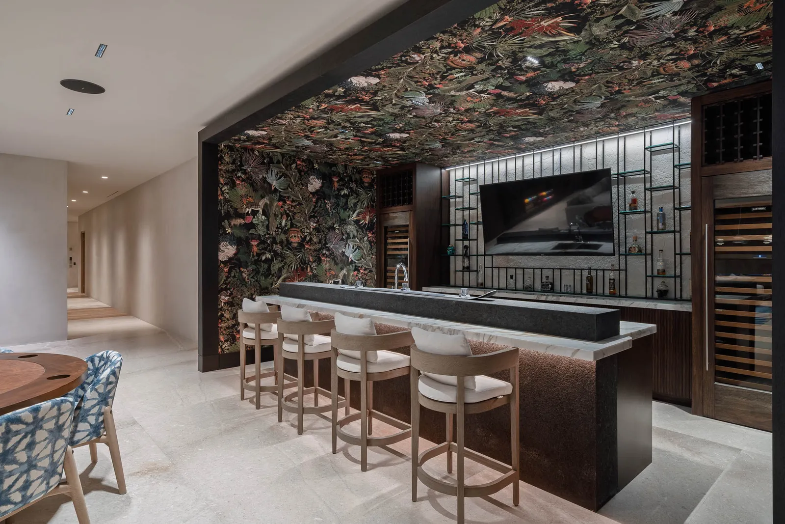 The botanical bar — stools beneath the jungle-print ceiling, wine fridges glowing