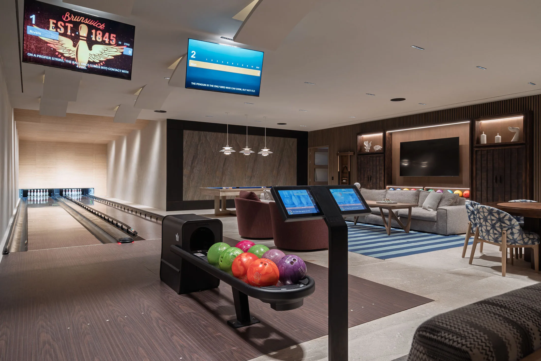 The entertainment level in one view — the two bowling lanes, ball return, pool table and lounge