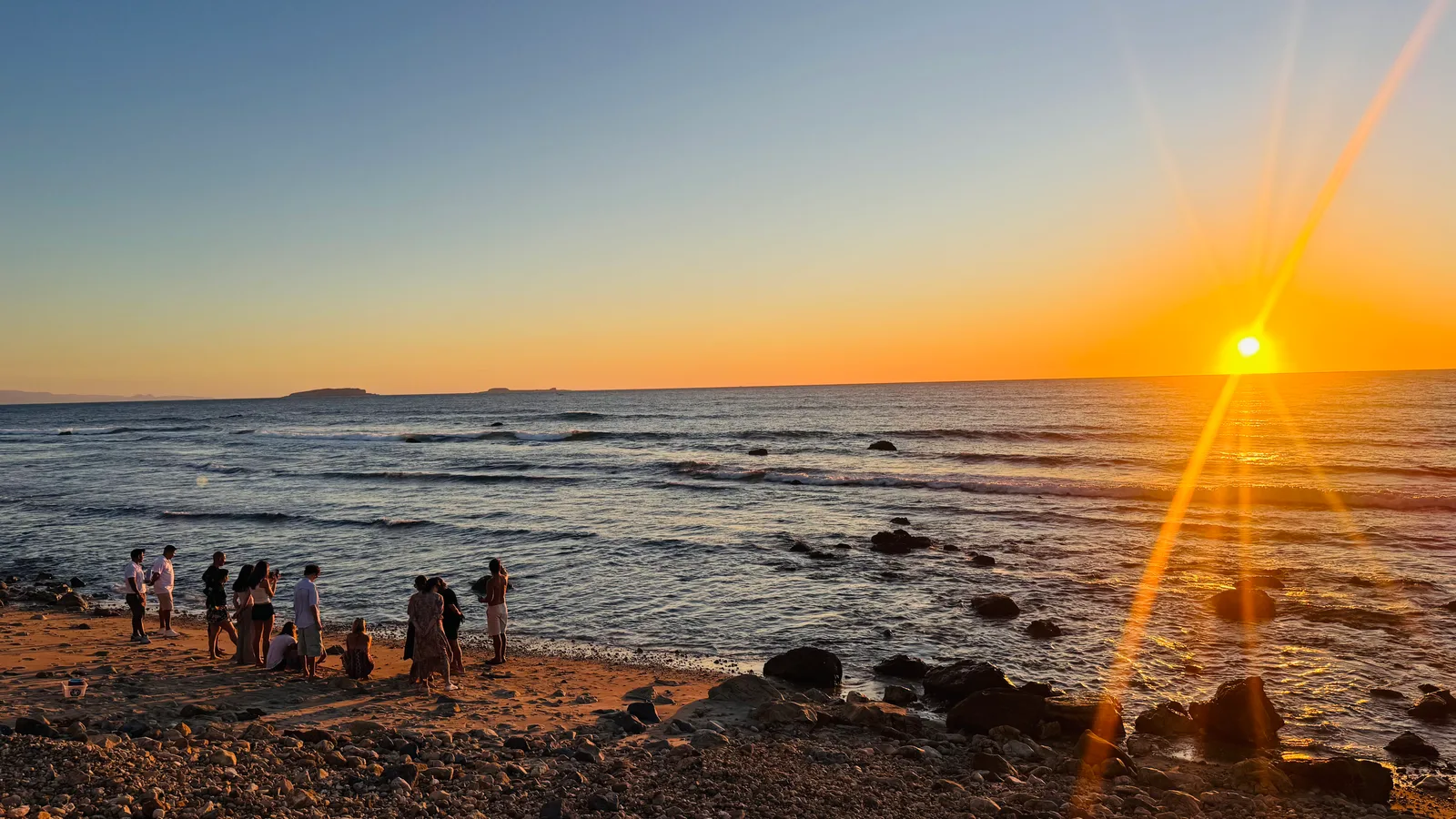 Guests gathered at the shoreline at sunset for a turtle release