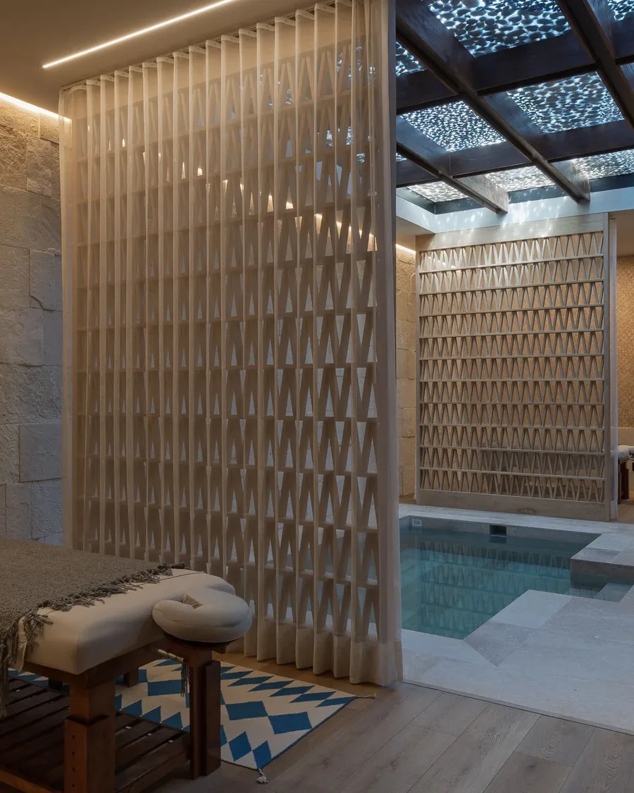 The spa suite — a massage table before the lattice screen, the cold plunge and dappled ceiling beyond