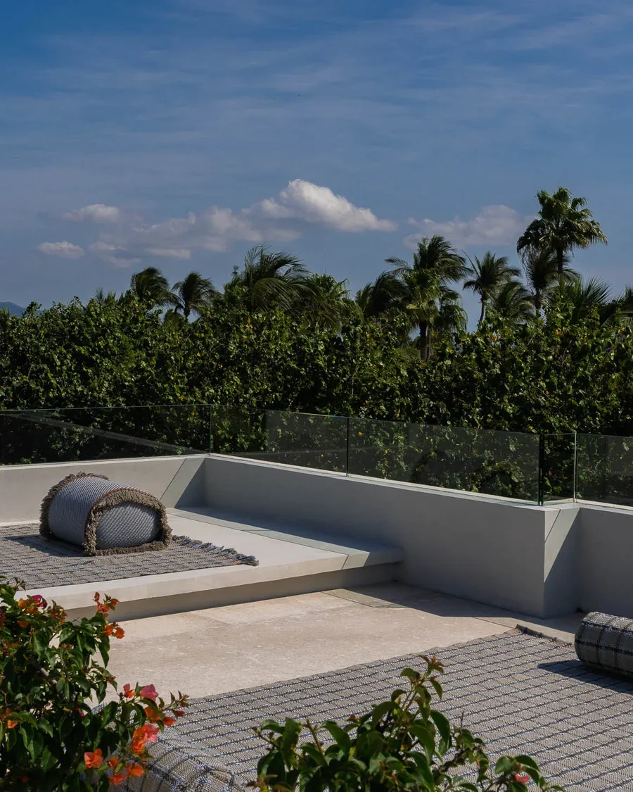 The rooftop yoga deck — a rolled mat and bolster on the terrace, palms and morning sky beyond