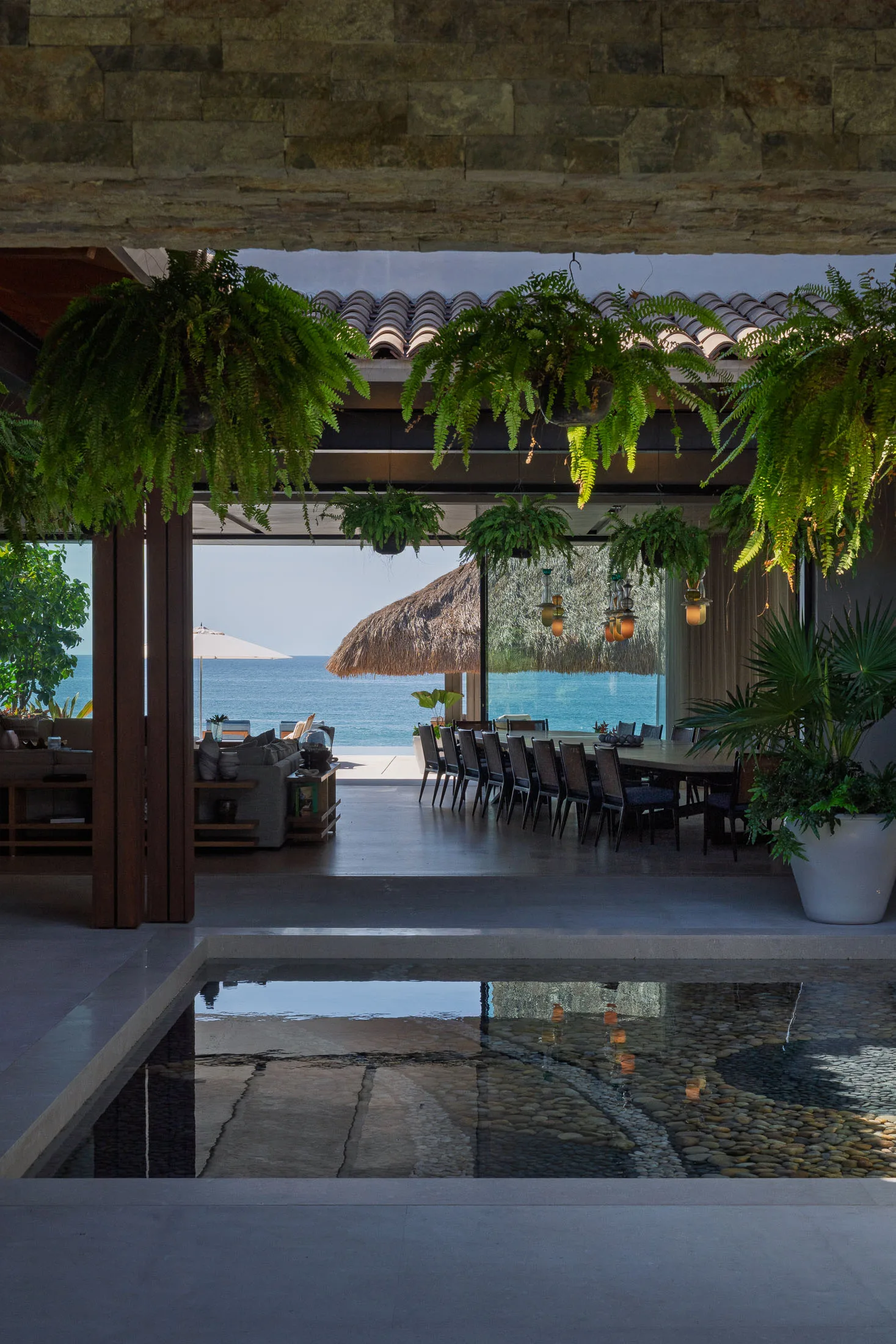 The great room — ferns overhead, open straight through to the ocean