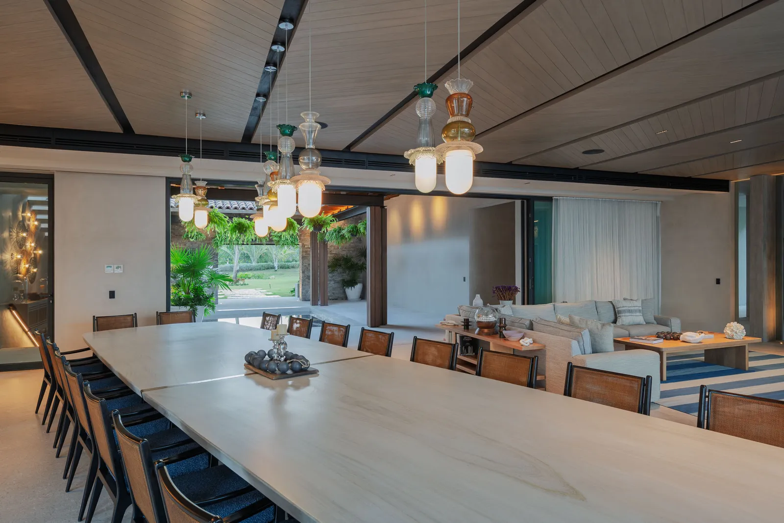Down the long dining table toward the lounge, pendant lights above