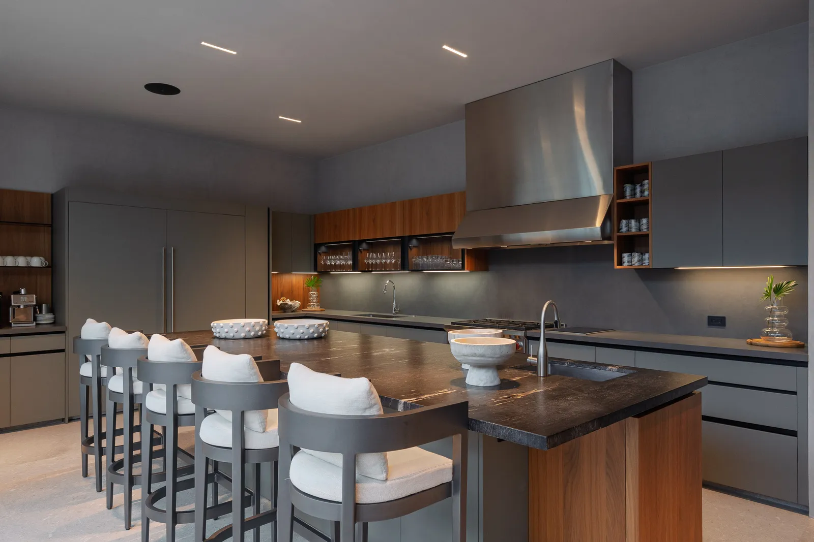 Stools lined along the stone island, the range and cabinetry behind