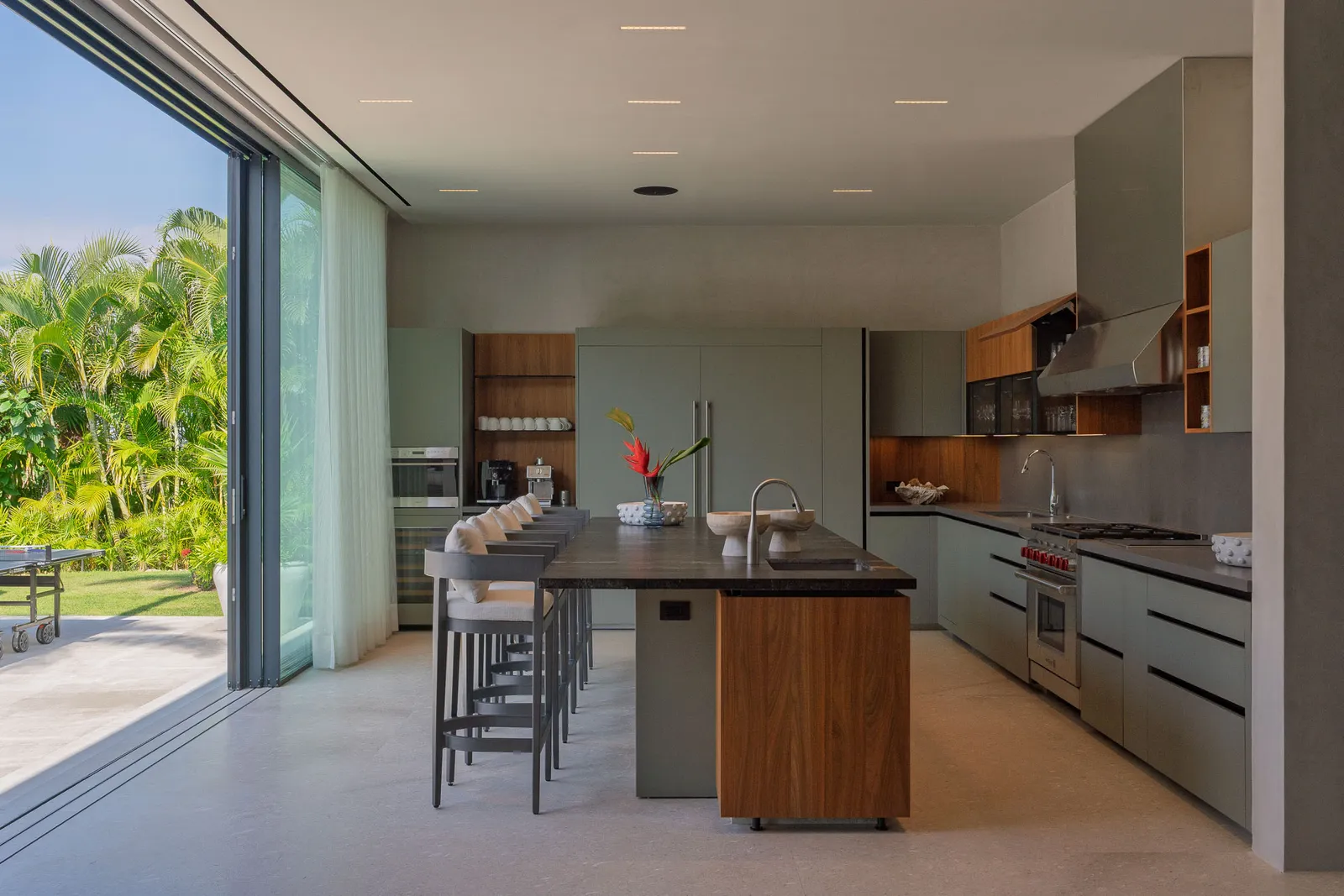 The kitchen with its glass wall open to the gardens and ping-pong terrace