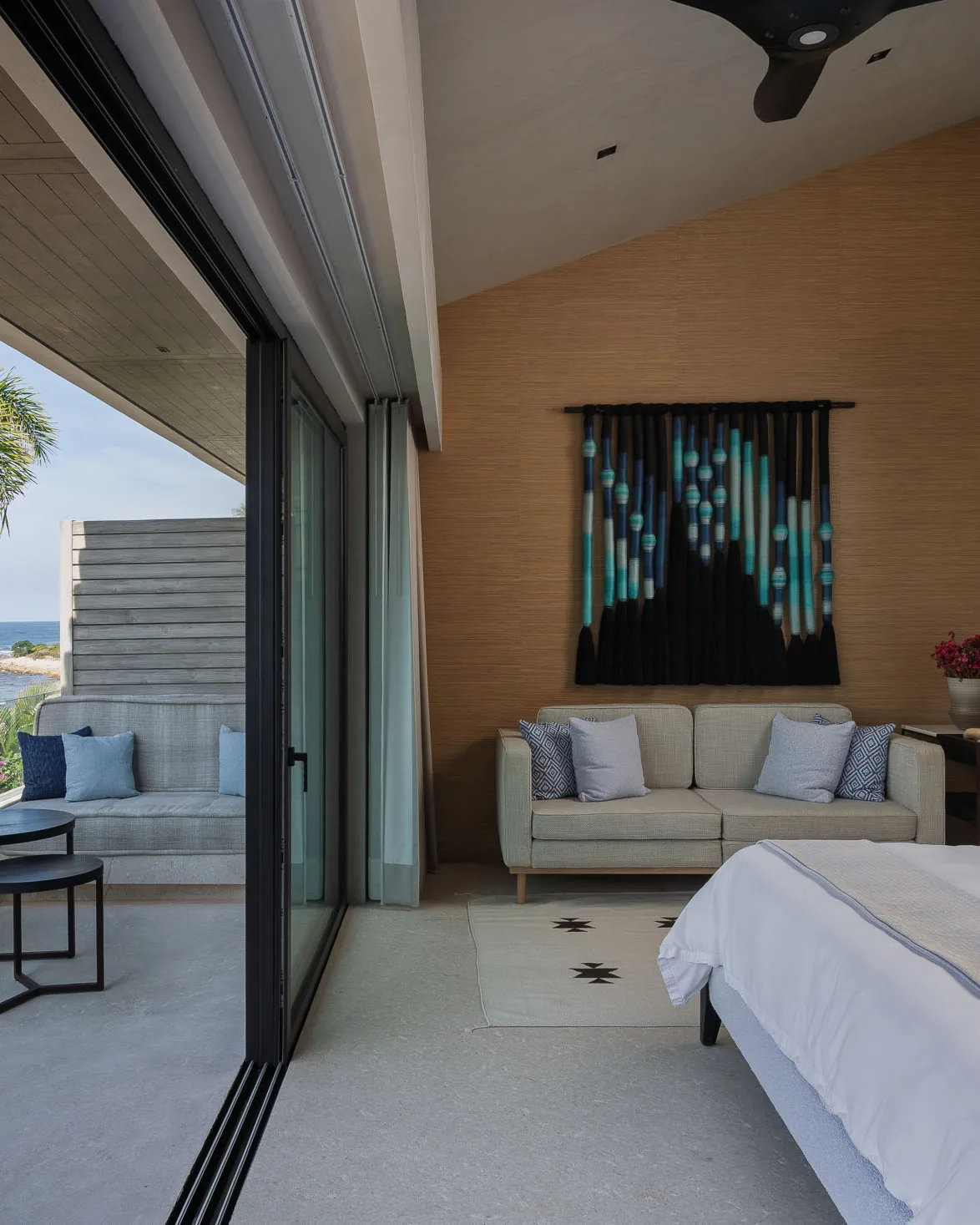 The Mountain Suite — sofa, woven wall hanging and the terrace toward the palms