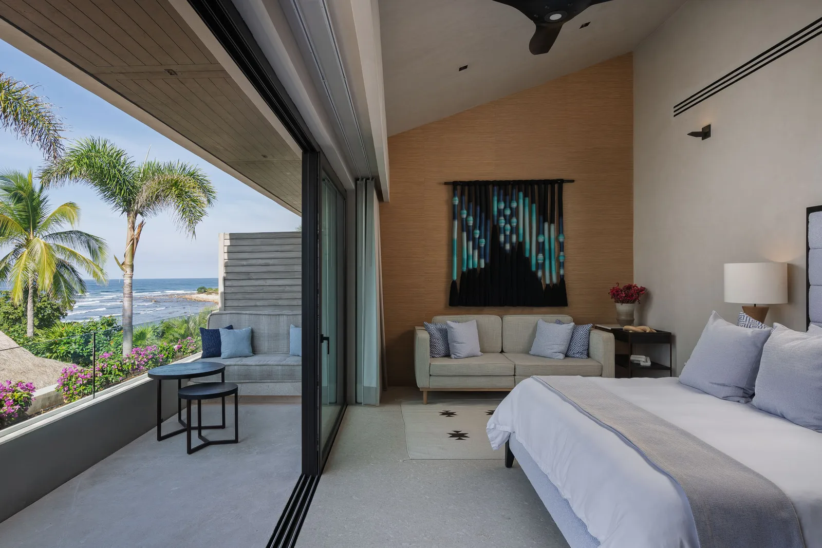 The Mountain Suite — sofa, woven wall hanging and the terrace toward the palms