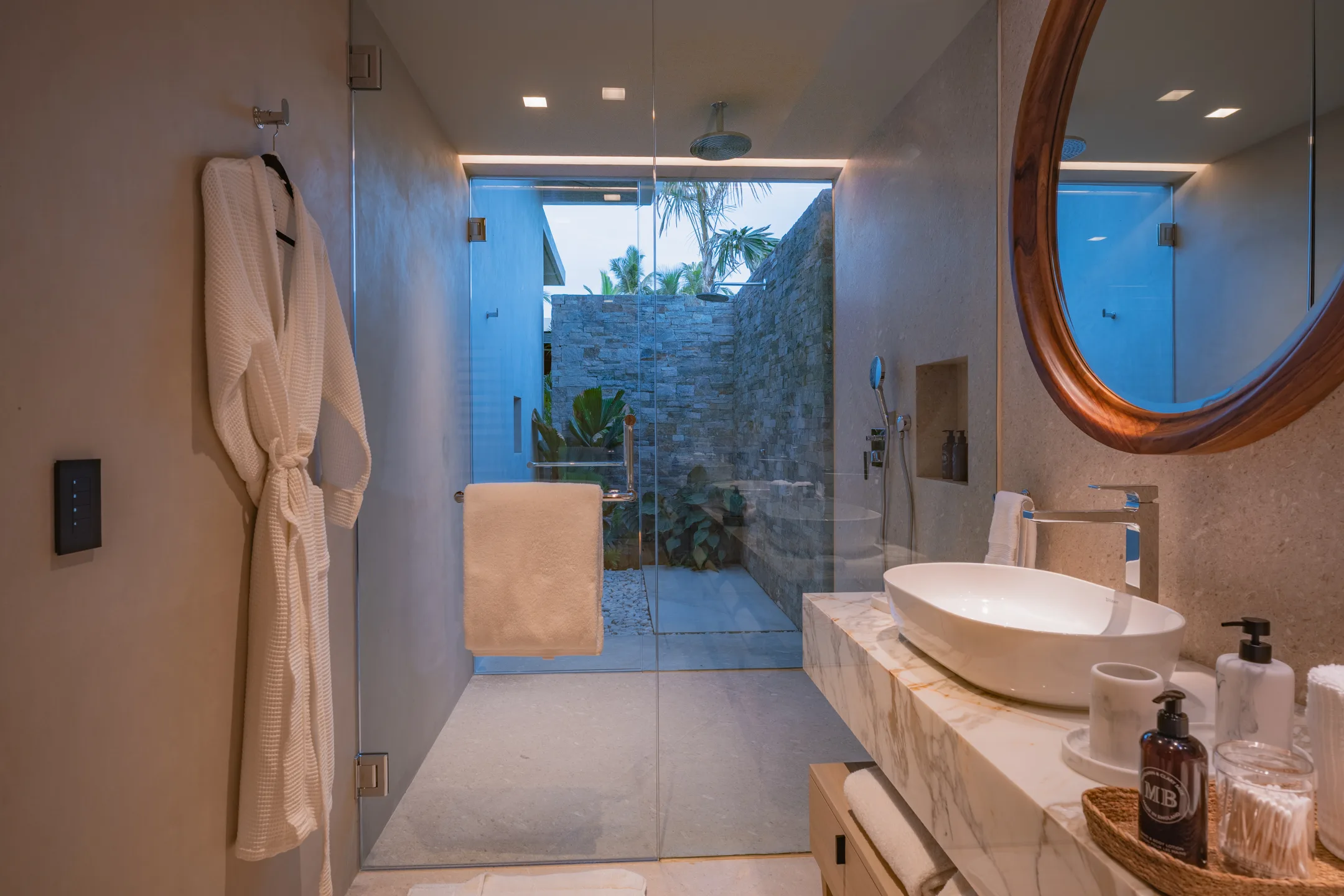 Inside Nature’s stone shower court — robe hung, sky overhead