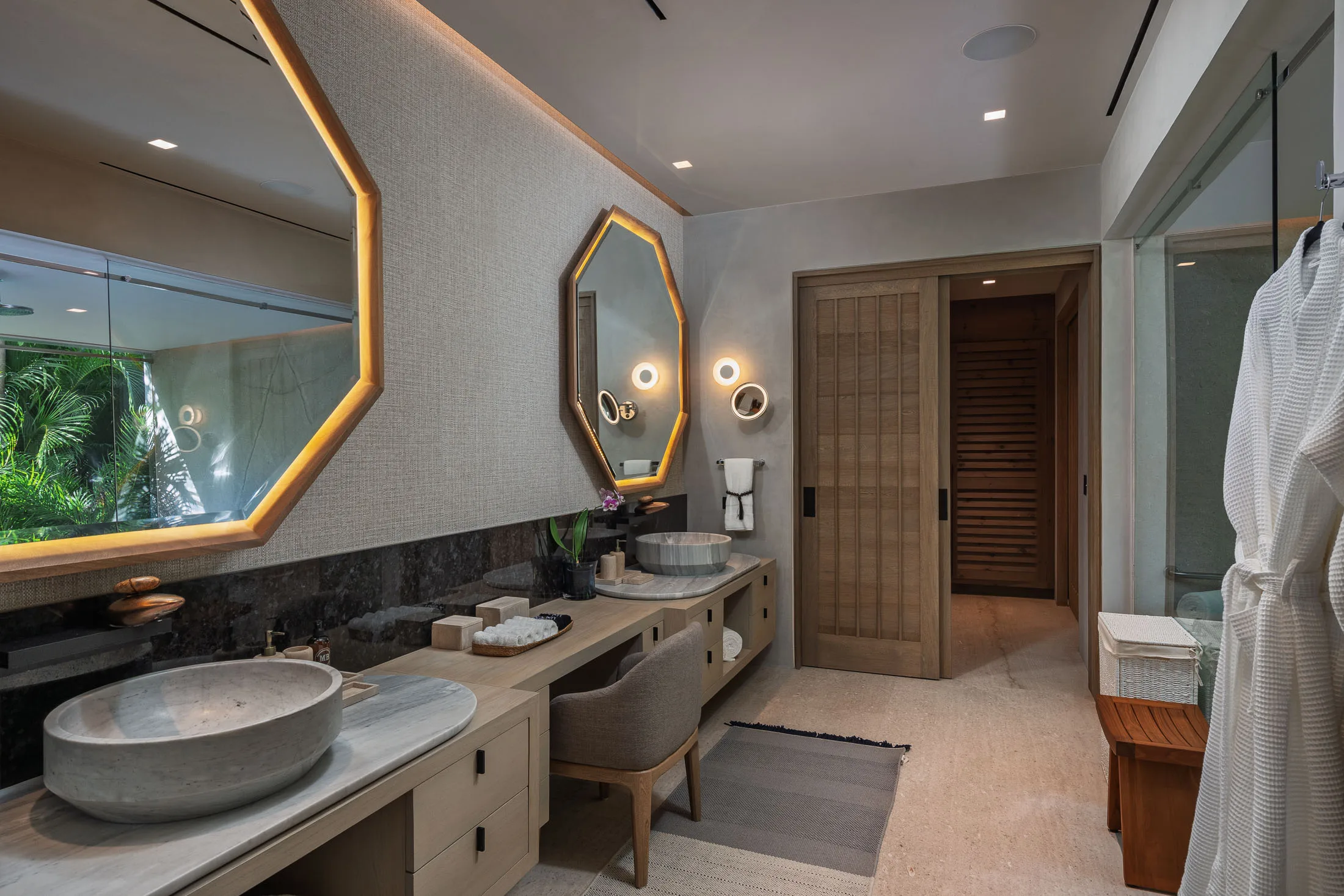 The Ocean Suite bath — carved stone basin beneath the lit octagonal mirror