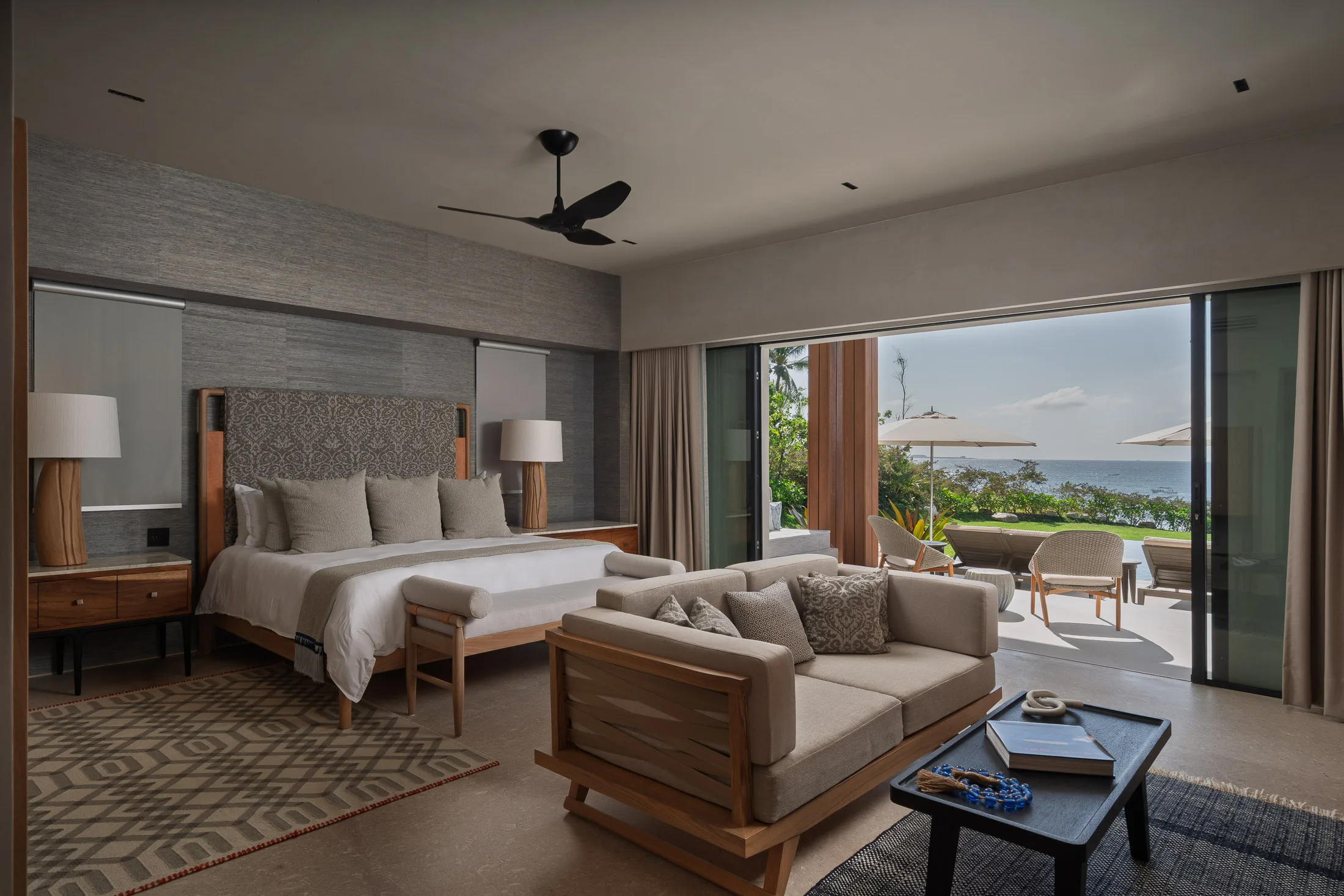 The Ocean Suite from its sitting side — the sofa at the foot of the bed, the terrace straight beyond