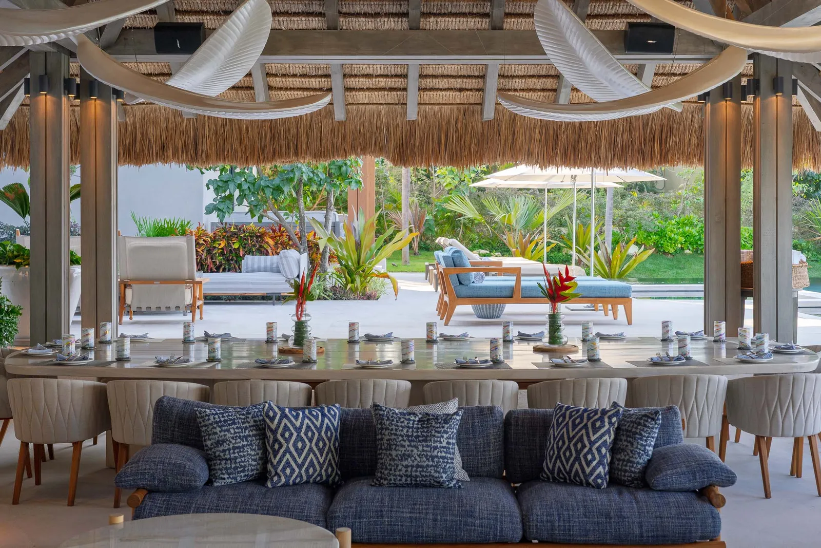 The palapa table and lounge in daylight, gardens and umbrellas beyond