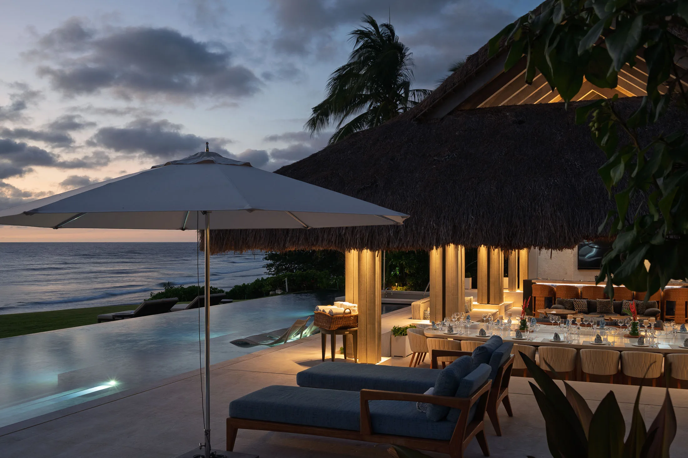 The palapa from across the pool at dusk, its lights warm under the thatch