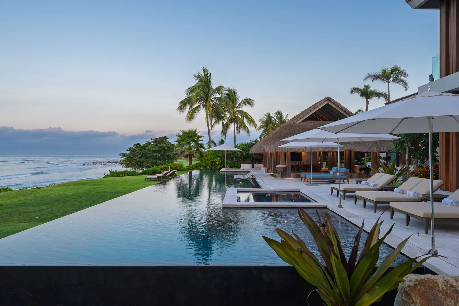 The pool running the length of the house under umbrellas, the ocean beyond