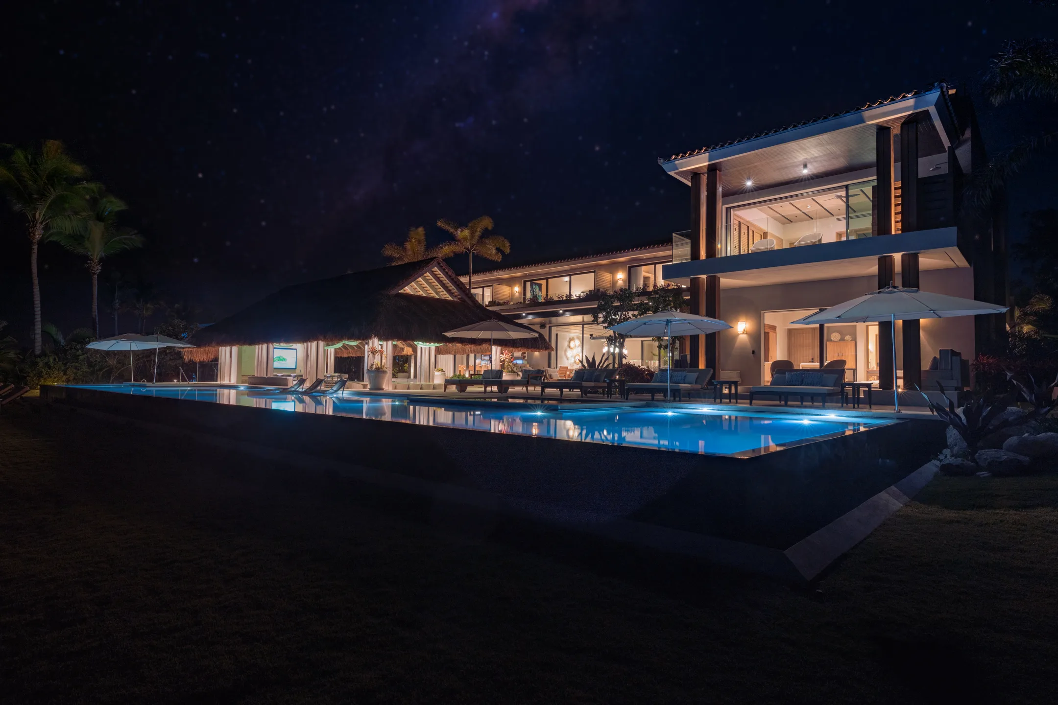 The house and the lit pool at night beneath the Milky Way