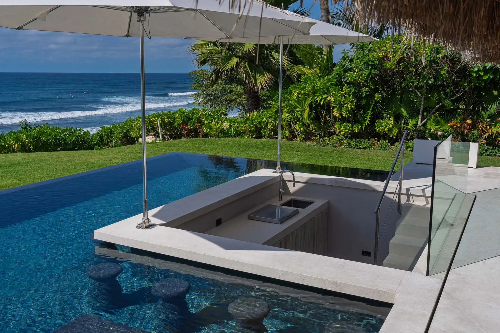The swim-up bar — stools set in the water beneath the umbrella