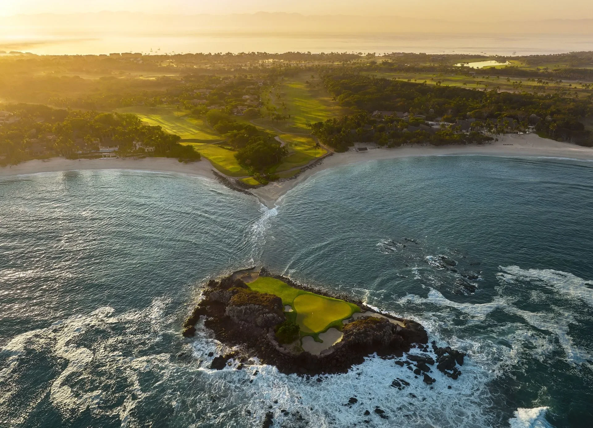 Pacífico’s island green at sunrise — the Tail of the Whale, waves breaking on the rocks around it, the fairway and coast behind