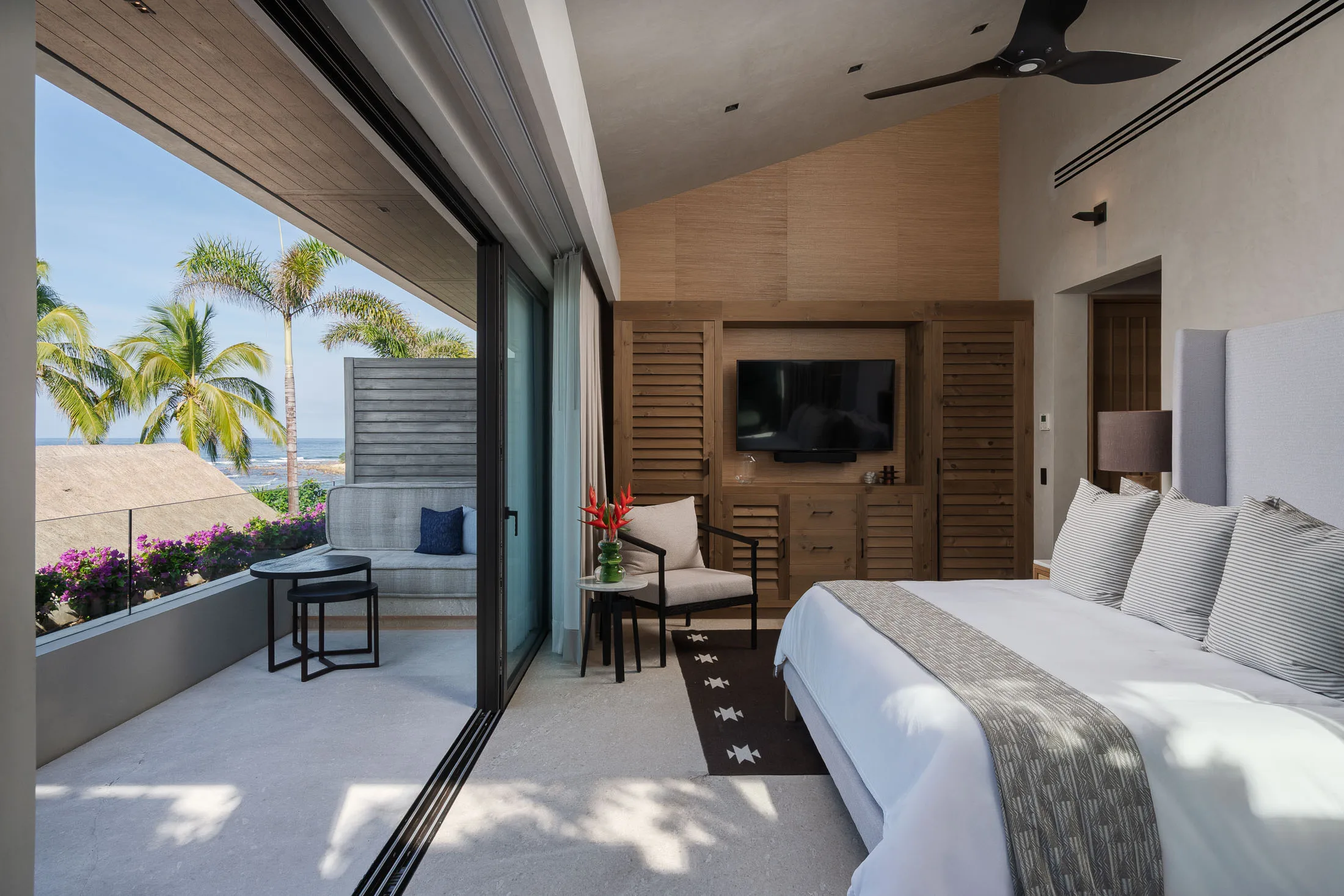 The Rivers Suite — king bed beside its private terrace, bougainvillea past the rail