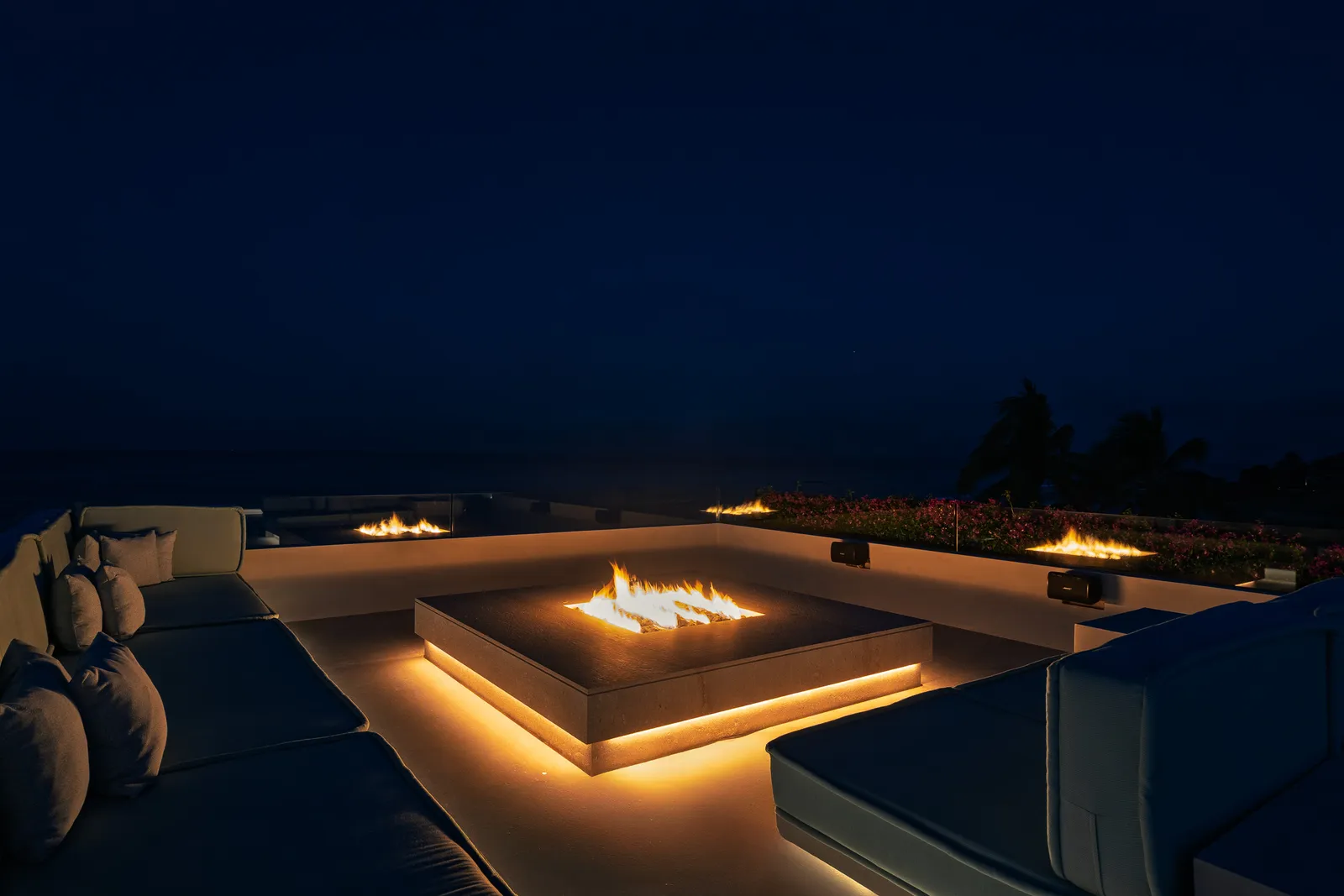 The fire table burning late, the lounge underlit against the dark