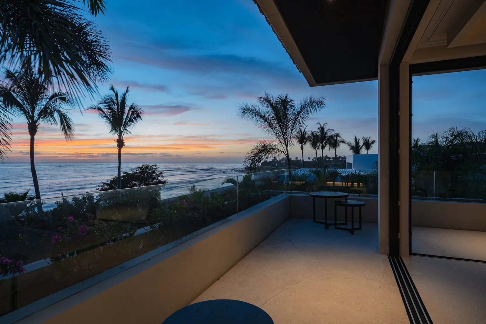 Sunset through Skye’s corner glass — palms black against the orange sky