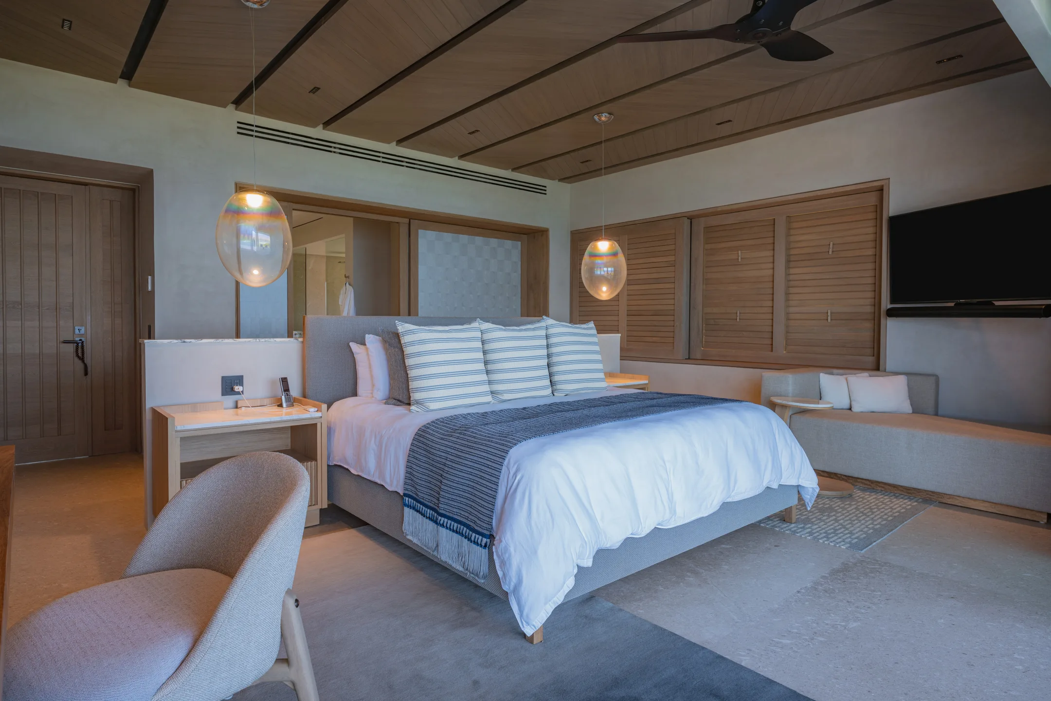 The Star Suite’s bed against its paneled wall, pendant lights either side