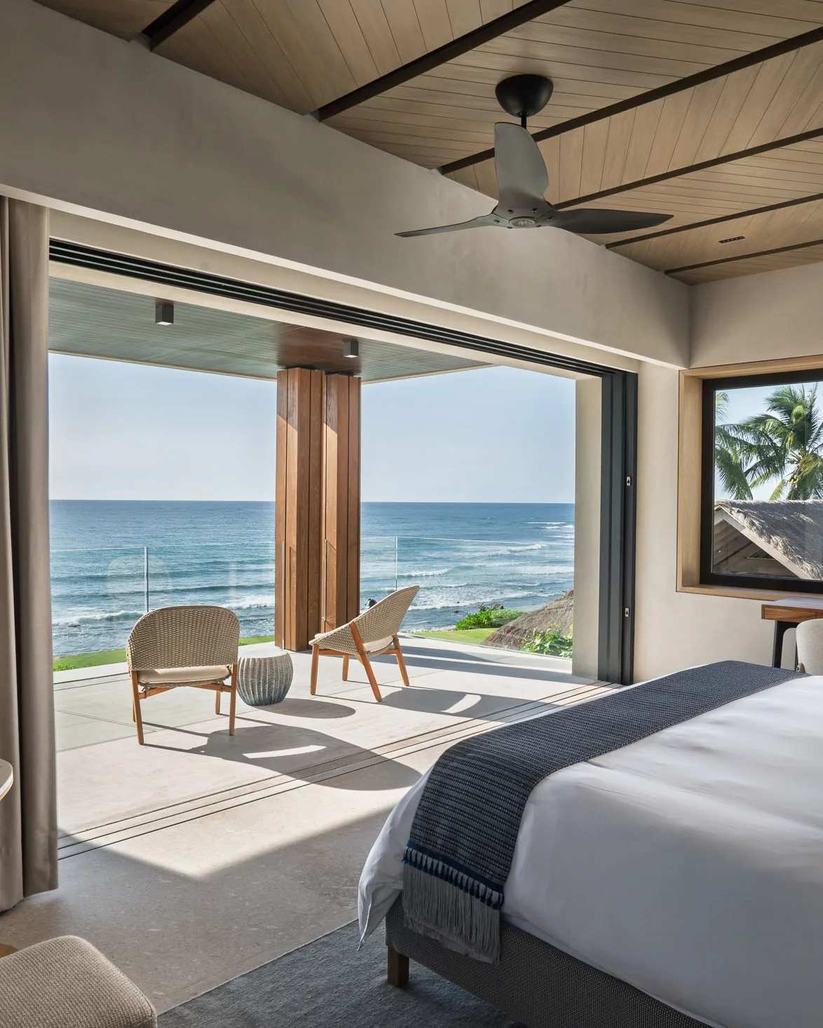 The Star Suite — the king facing corner glass and the ocean beyond the palms