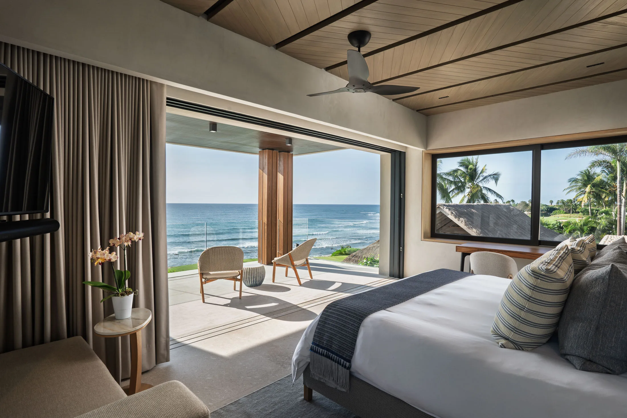 The Star Suite — the king facing corner glass and the ocean beyond the palms
