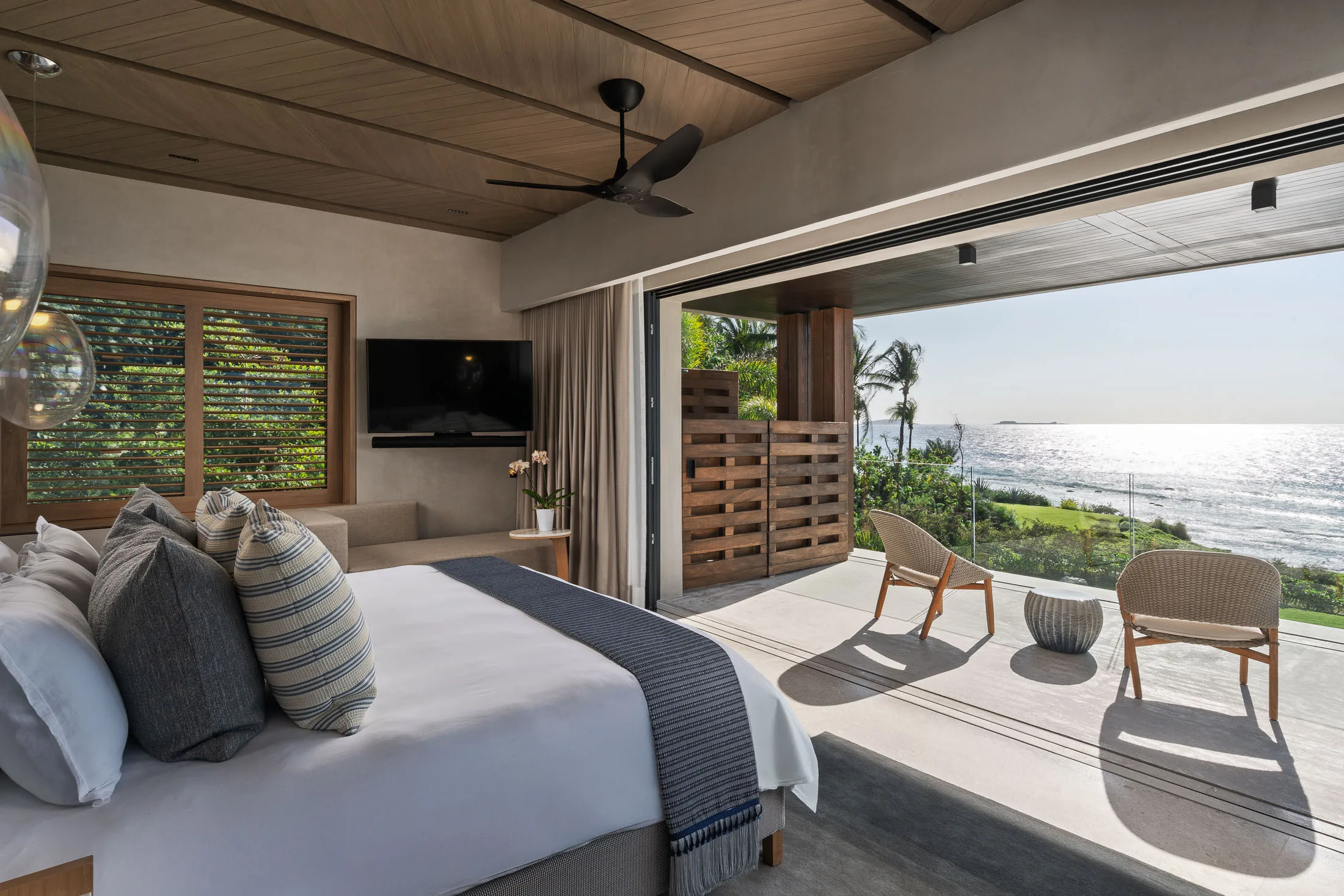The Star Suite with its corner folded open — the bed, the terrace chairs and the light on the water