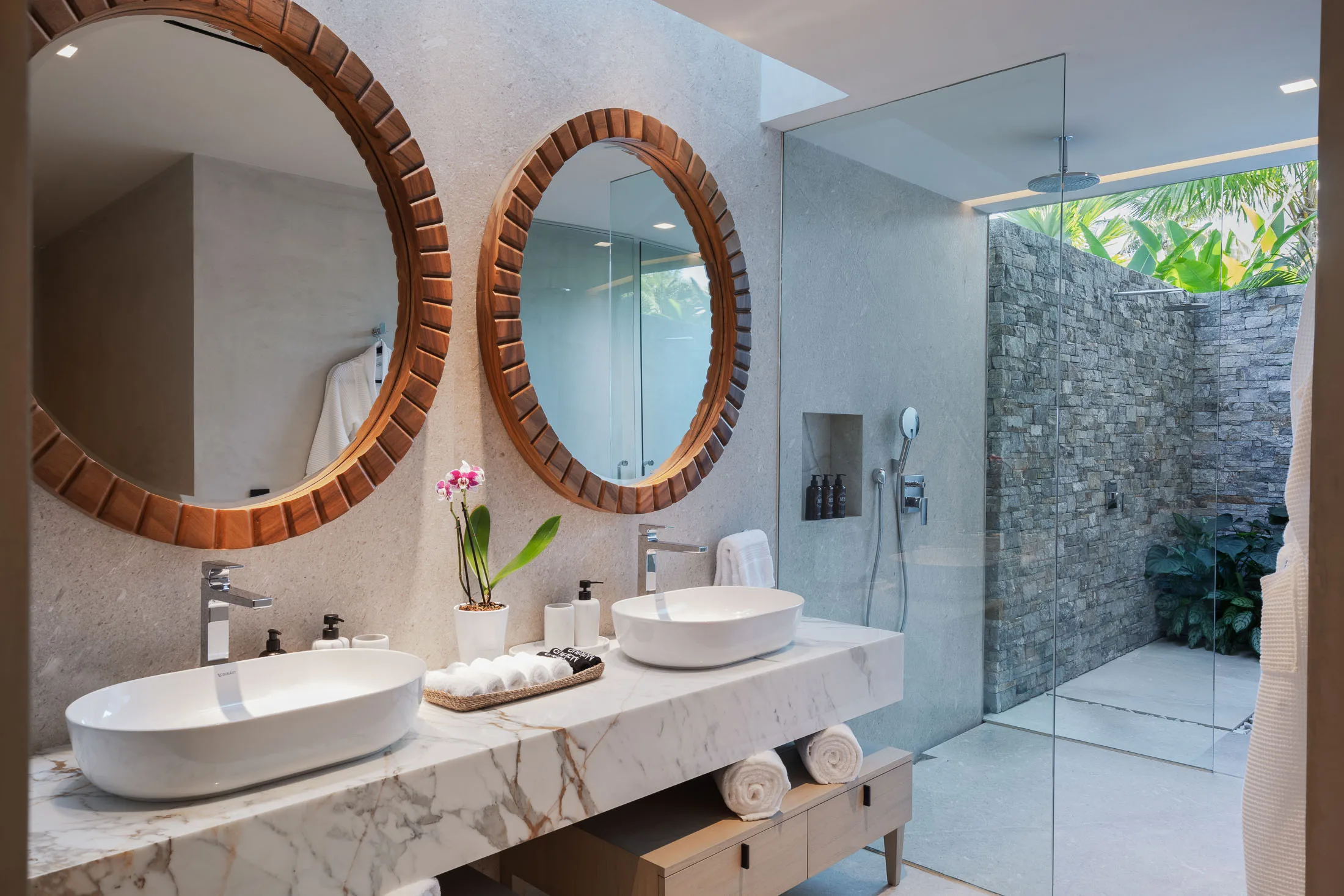 Stepping Stone’s bath — twin round mirrors, glass shower and the stone outdoor shower beyond